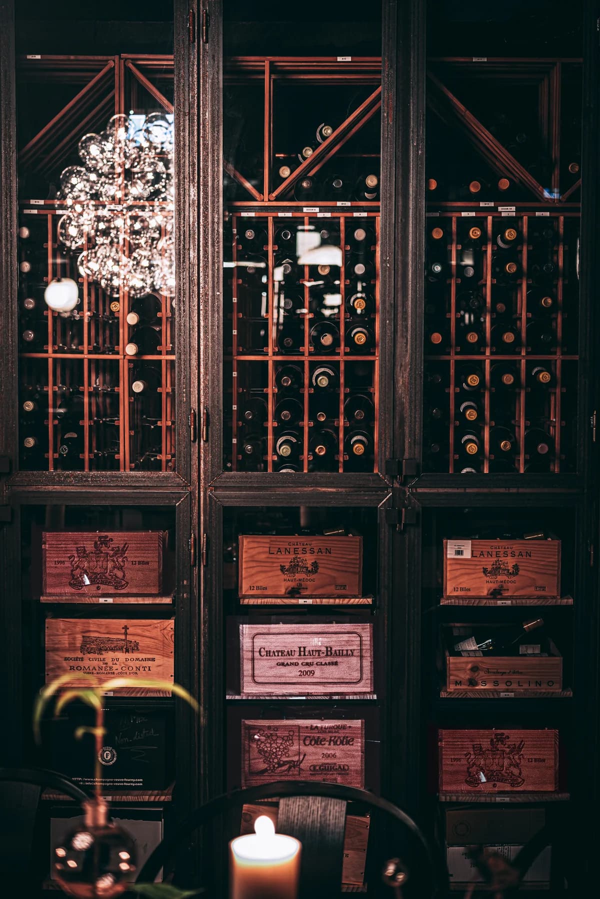 Glass-fronted wine cabinets and wooden wine cases beside a candlelit table